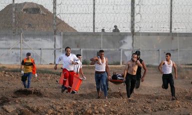 People including medics run away from Israeli army position while carrying person on stretcher