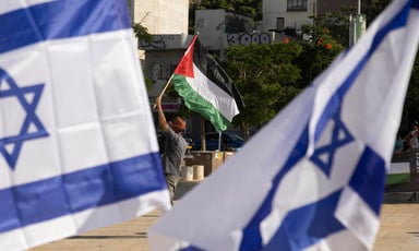 Person holds Palestine flag among group of Israeli flags