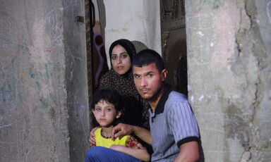 Joud al-Amarin, age 6, who was diagnosed with leukemia, stands near her mother and father.