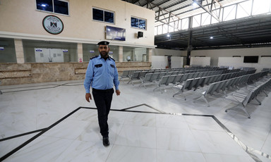 A man in uniform walks in front of empty seats in large hall