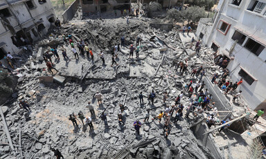 People stand atop the ruins of a destroyed building 