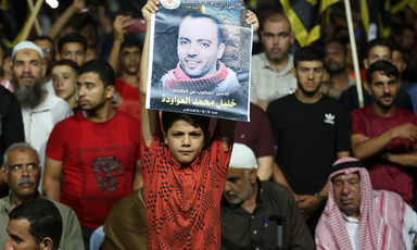 A child holds up a poster of a man as people stand behind him