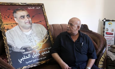 Man sits on couch next to framed poster of Mohammed El Halabi