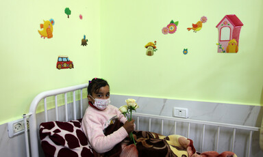 A child in a face mask lies on a hospital bed at the Rantisi Hospital in Gaza.