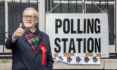 A man gives a thumbs up standing next to a polling station