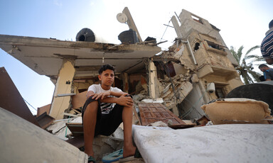 A child sits atop the rubble of a destroyed building in Gaza