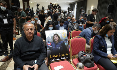 A poster on a chair in a room crowded with journalists