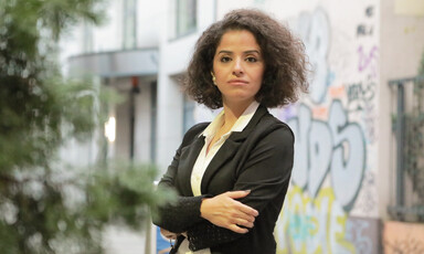 A woman stands with arms folded