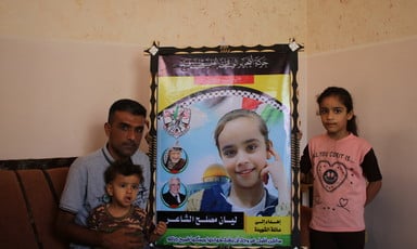 Man and two children beside a large photograph of a girl 