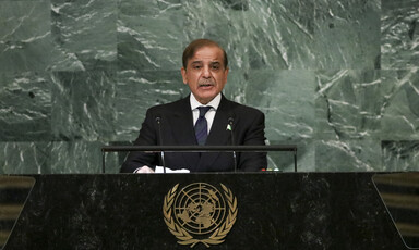 Man stands at a podium with a backdrop of green stone behind him