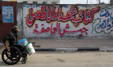 A Palestinian man in Gaza traveling down the street in a wheelchair