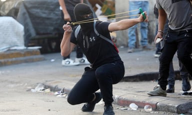 A masked man aims a slingshot