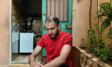 A man sits with his hands resting on his knee