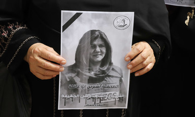 Close-up of two hands holding a black and white poster of Shireen Abu Akleh
