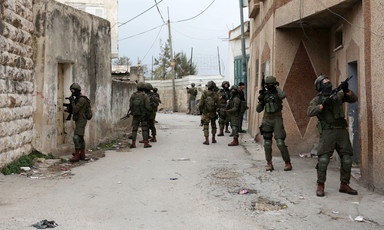Heavily armed soldiers search between buildings 