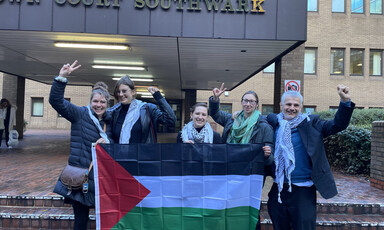 Five people stand behind a flag 