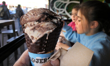 Close up of an ice cream cone with children behind it