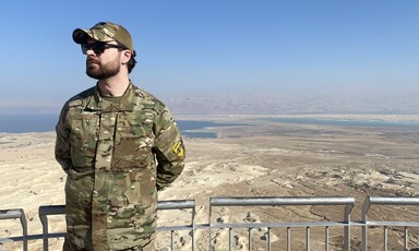 A man in military uniform overlooks a desert