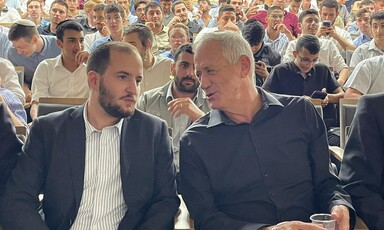 Two men sitting in an audience lean towards one another