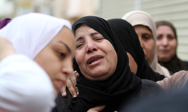 Women wearing headscarves crying and comforting each other 
