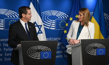 Israel's President Isaac Herzog stands on a podium beside European Parliament President Roberta Metsola 