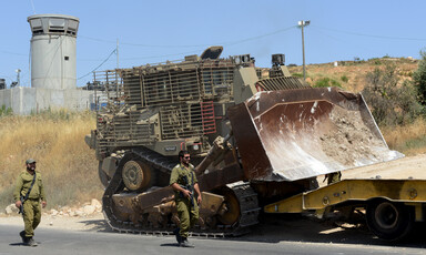 Armed soldiers beside a large bulldozer 