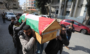 A group of men carry a coffin covered with a flag 