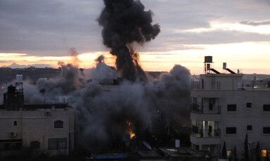 A plume of smoke rises from an explosion between two low-rise building
