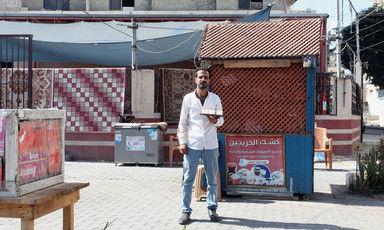 A man stands with a tray in front of a small wooden booth