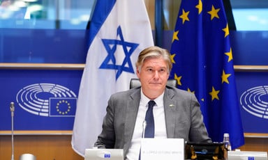 Member of the European Parliament Antonio López-Istúriz sits at a desk with the Israeli and European Union flags behind him