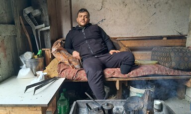 A man sits with his amputated leg on a narrow bed