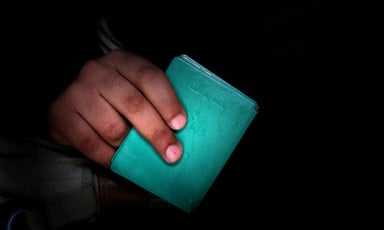An up-close image of a hand holding a green Palestinian ID document