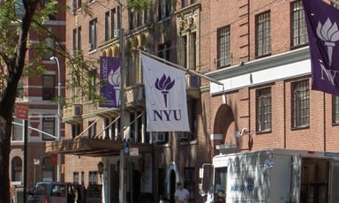 Banners with the NYU logo hang from brick buildings