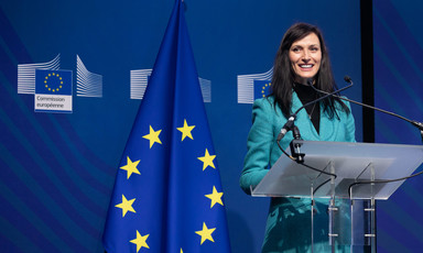 Mariya Gabriel stands at a podium with a large EU flag beside her