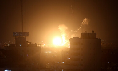 A bright explosion and smoke over city skyline at night