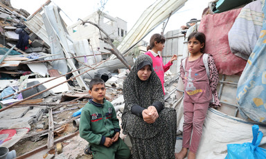 Women and children sit atop concrete rubble