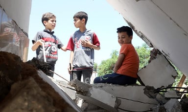 Children play in the rubble of a destroyed house.