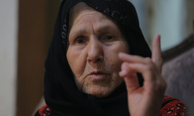 An elderly woman gesticulates with her finger