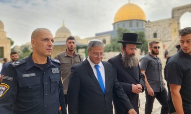 Itamar Ben-Gvir walks beside other men, some wearing police and military uniforms, with the Dome of the Rock in the background 