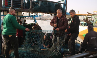 Three men handle a fishing net 