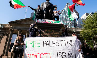 ctivists hold a large free palestine banner and flags in front of a statue and a neo-classical building
