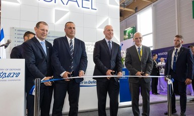 Israel's Defense Minister Yoav Gallant and a number of other men hold a scissors to a ribbon with a sign reading Israel in large letters behind them