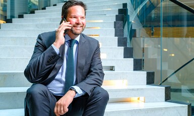 Austrian politician Lukas Mandl sits on steps while holding a mobile phone to his ear