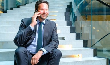 Austrian politician Lukas Mandl sits on steps while holding a mobile phone to his ear 