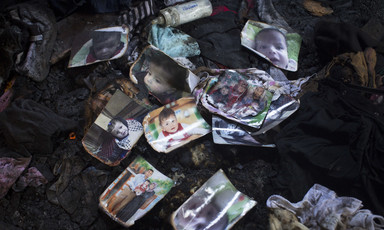 Fire-damaged photos of baby are strewn on top of clothing dirty with soot