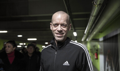 Salah Hammouri, seen from chest up, smiles while standing in dark corridor