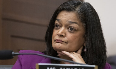 Pramila Jayapal holds her chin in her hands behind a nameplate.