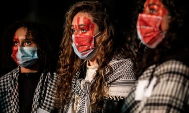 Three women with their faces painted blood red