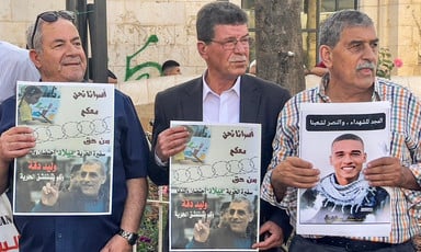 Three men hold up protest signs with images depicting Palestinian prisoners and also Egyptian police conscript Muhammad Salah