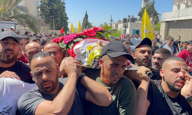 Men carry the corpse of a child on a stretcher, wrapped in flags, during his funeral 